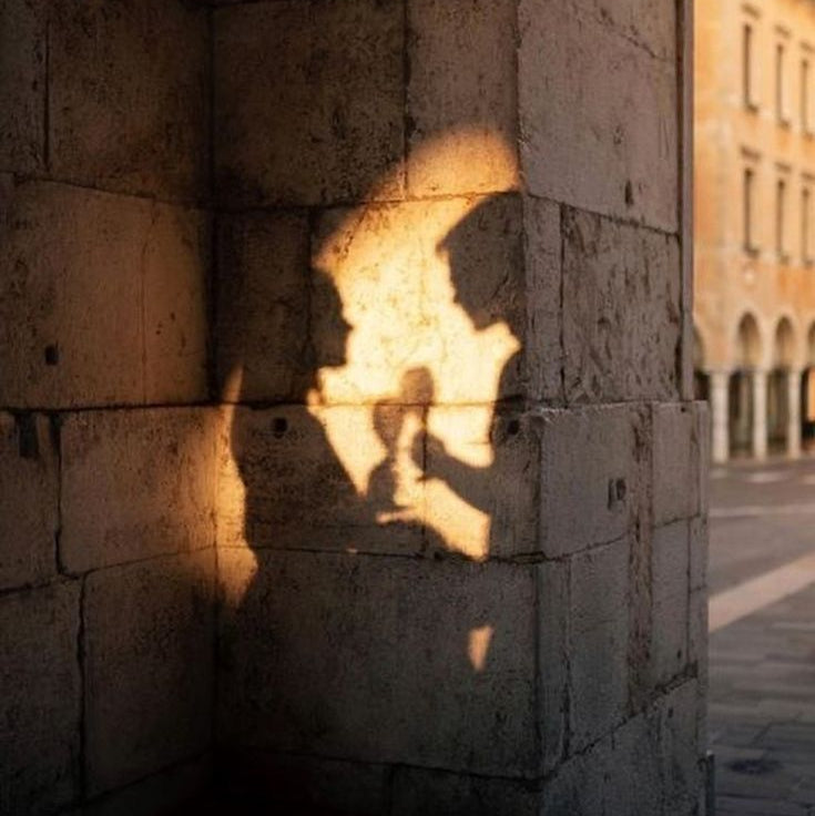 Shadow of a person holding a camera on a stone wall