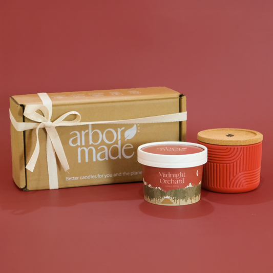 Two candles and a box with 'arbor made' branding on a red background